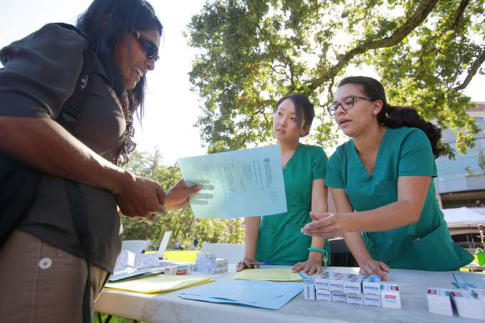 Dental students giving program information flyer to an interested student on campus